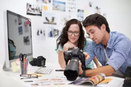 Two young photographers looking at photos on a digital camera in their studio