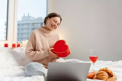 Woman holding gift box using laptop, online dating. Distance relationship, love, Valentines Day